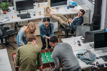 Junge Arbeitnehmer kickern im Büro
