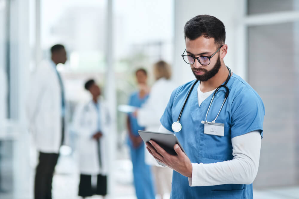 Junger Mediziner nutz in einem Krankenhaus ein digitales Tablet.