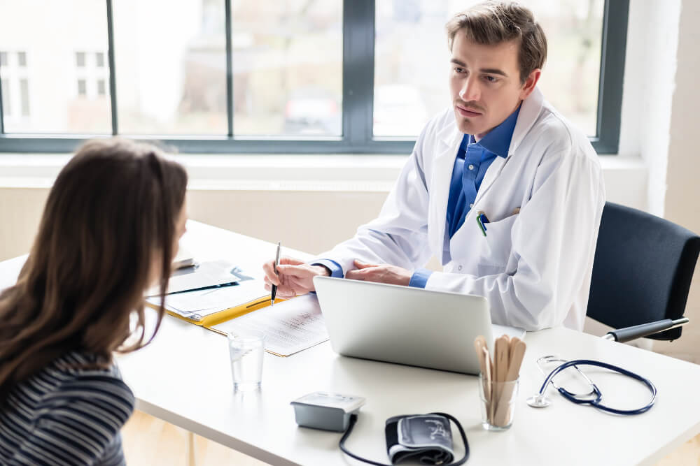 Ein junger Arzt hört einfühlsam und aufmerksam einer jungen Patientin zu.