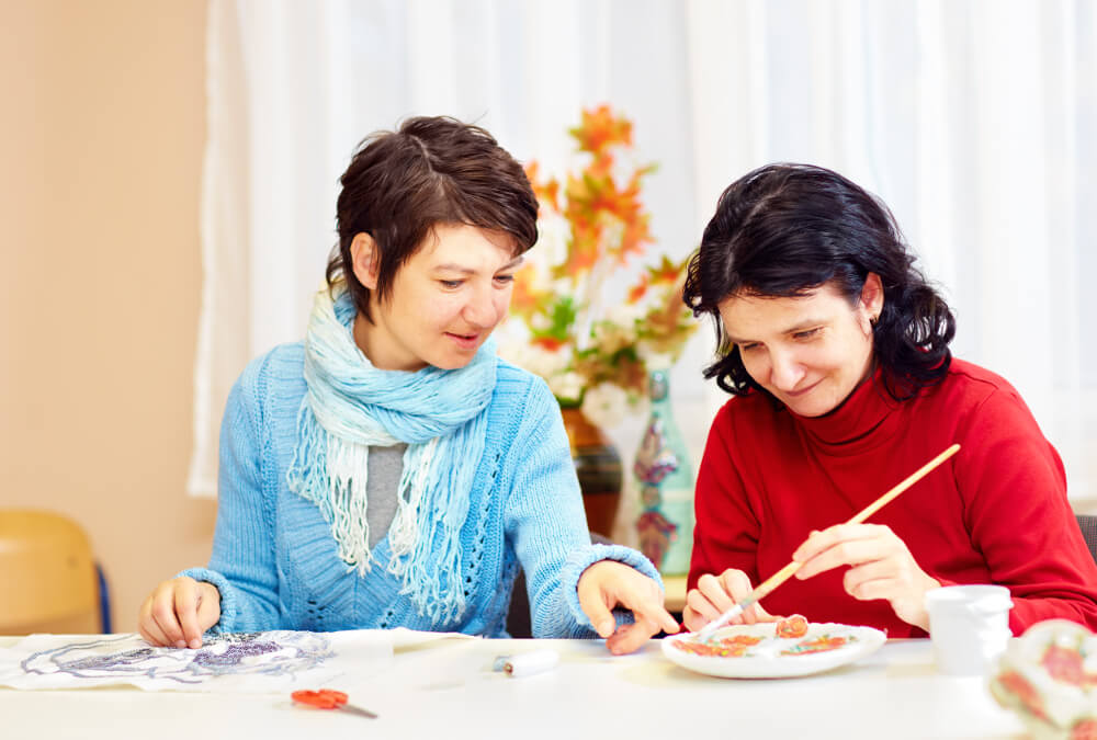 Zwei junge Frauen mit Behinderung arbeiten kreativ.