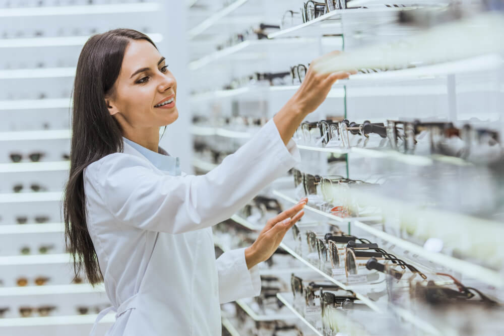 Eine Augenoptikerin sortiert eine Brille ins Verkaufsregal ein