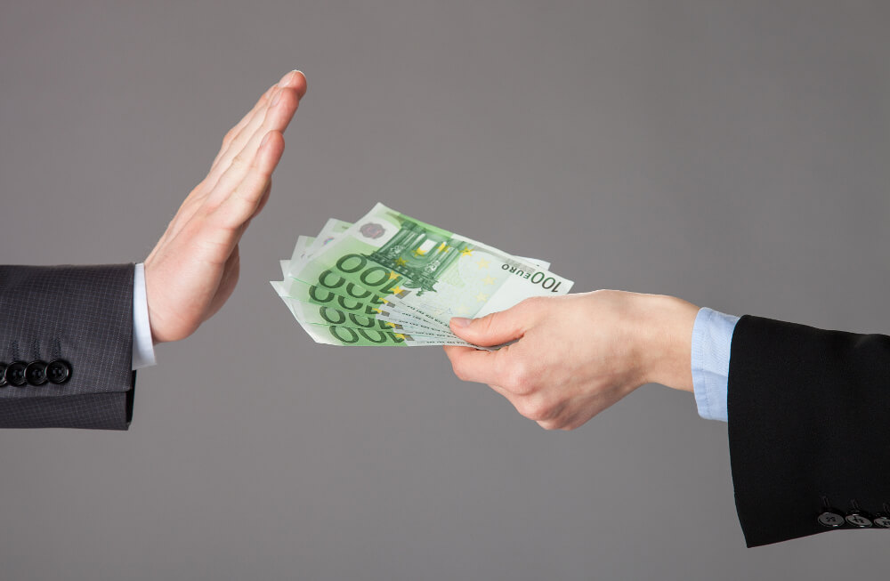 Ein Mann verzichtet mit einer ablehnenden Geste auf ihm angebotenes Geld.