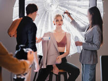 Stylist, der eine Fusselrolle benutzt, und Hairstylist, der einem stilvollen Modell hinter der Bühne eine Frisur verpasst.