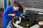 Kfz-Mechatronikern prüft Ölstand an einem Auto