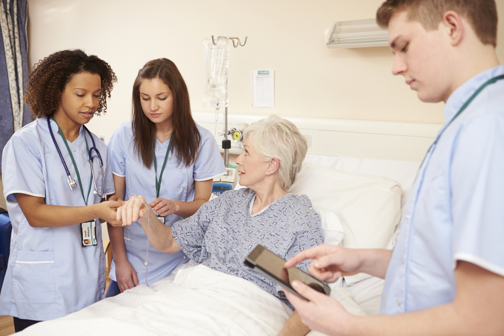 Azubis in der Pflege erhalten Anleitung am Patienten
