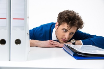 Müder Arbeitnehmer schaut auf die Uhr