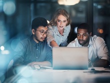 Drei Personen arbeiten spät am Laptop