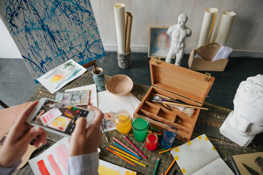 Künstler*in fotografiert Werk mit Smartphone