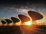 Große Radioteleskope für Astronomen stehen bei untergehender Sonne unter einem Sternenhimmel.