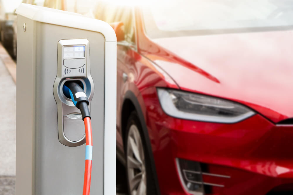 Ein roter Tesla steht vor einer Ladestation.
