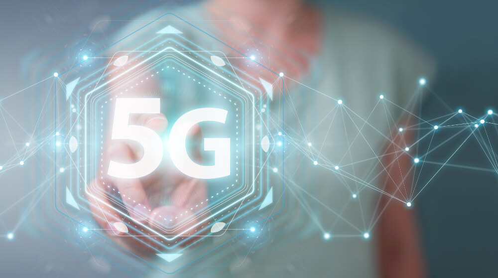 Eine Projektion zu 5G wird an einem interaktiven Board von einer Frau bearbeitet.
