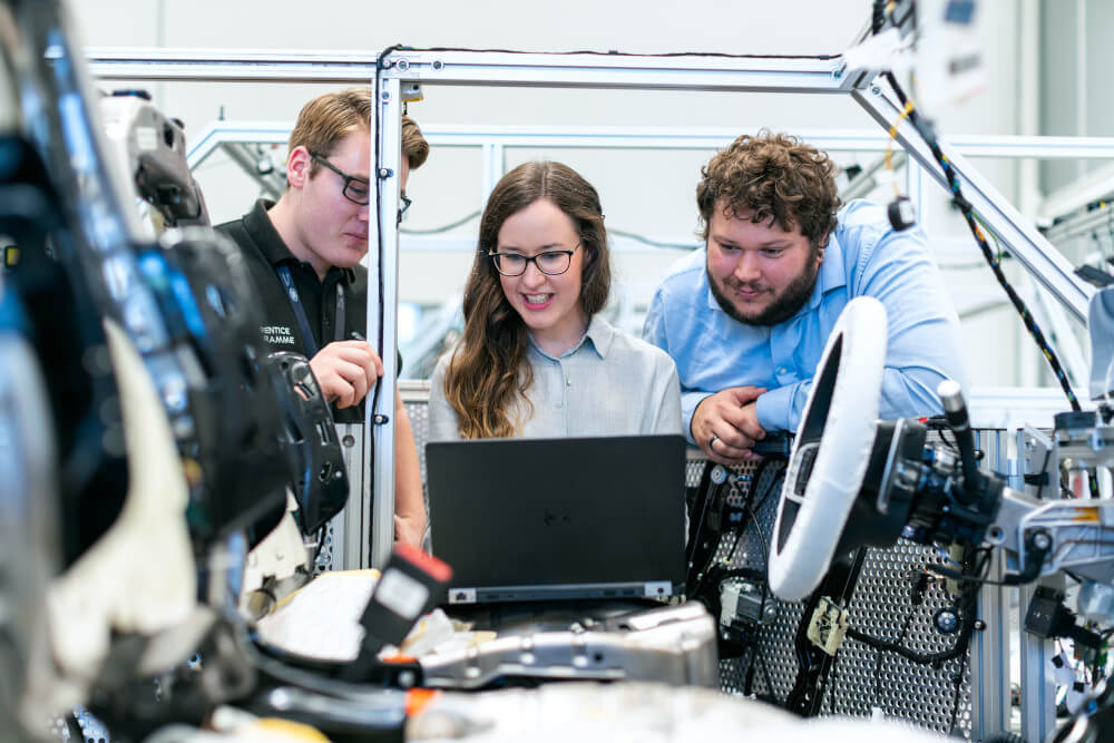 Ingenieure In einer Autowerkstatt schauen sich an einem Computer die neusten Entwicklungen an